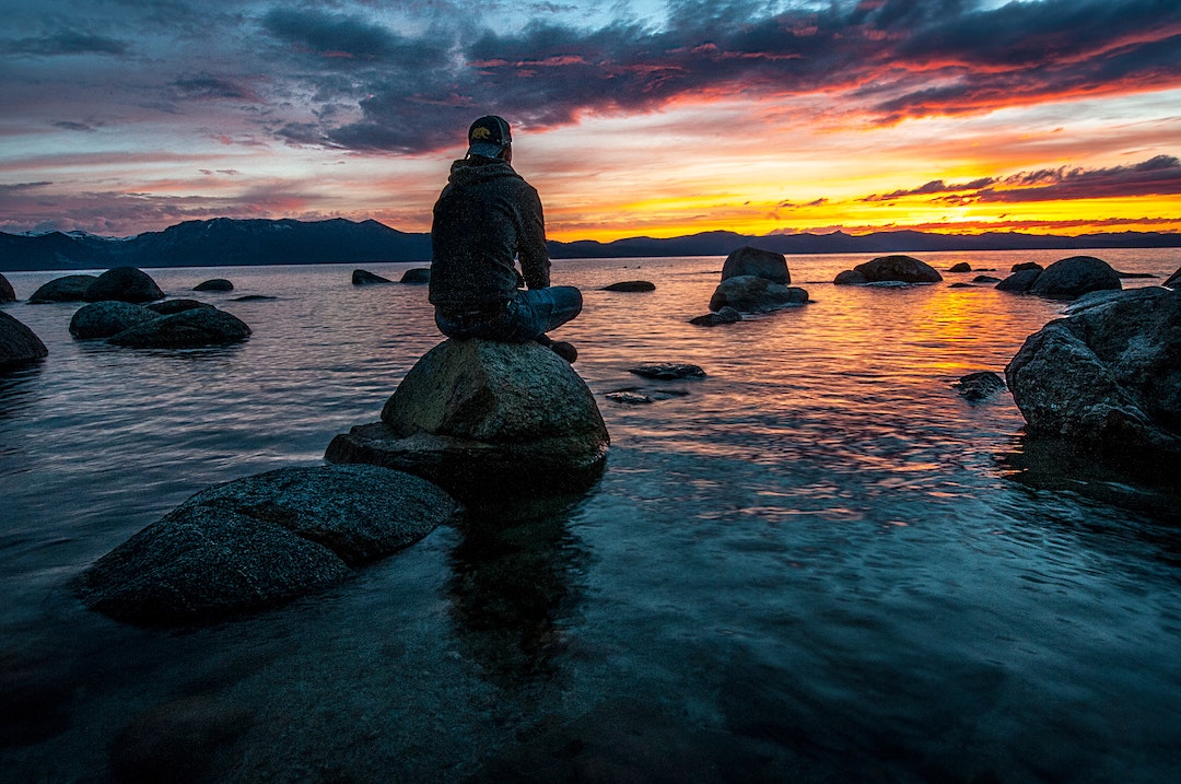 Man calmly sitting on a rock in a river